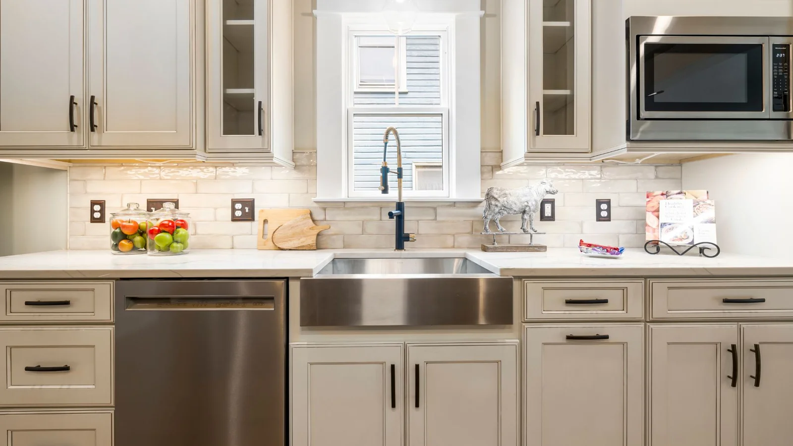 Kitchen with gray shaker cabinets, stainless farmhouse sink, subway tile backsplash, and marble-look countertops