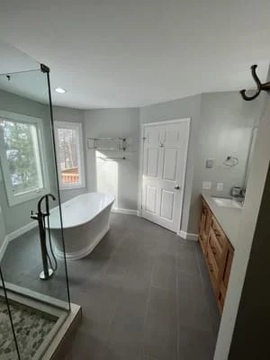 Bathroom with freestanding tub, glass walk-in shower, dark gray tile floor, and wood vanity with white countertop