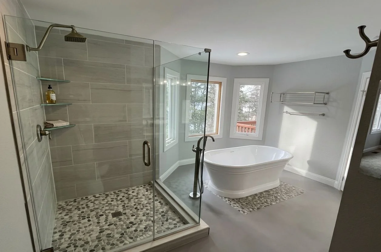A finished bathroom remodel in an Anchorage home showing a tiled walk-in shower, updated vanity, and new flooring. The space reflects durable, cold-climate construction suited to Alaska residential use.